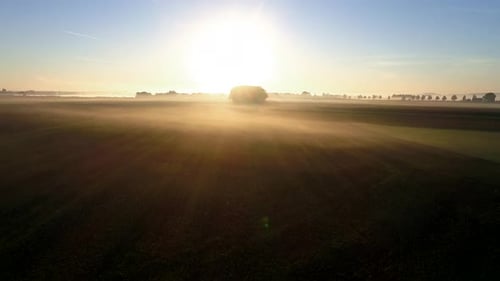 4K aerial slow motion flight at sunrise over foggy agricultural fields in germany