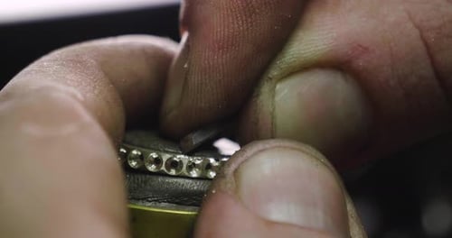 Nahaufnahme der Hände eines Goldschmieds bei der Arbeit an einem Diamantring. Konzept: Stil, Mode
