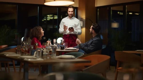 Restaurant Waiter Taking Order Serving Attractive Couple on Evening Dinner Date. Happy