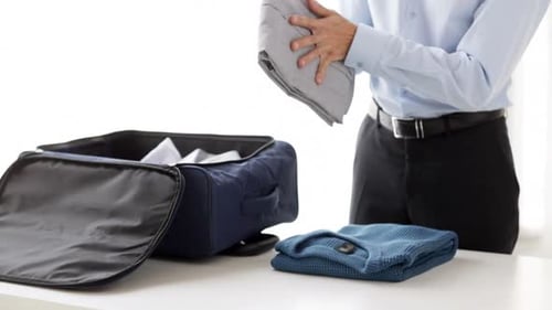 Man Packing Suitcase with Folded Clothes Indoors