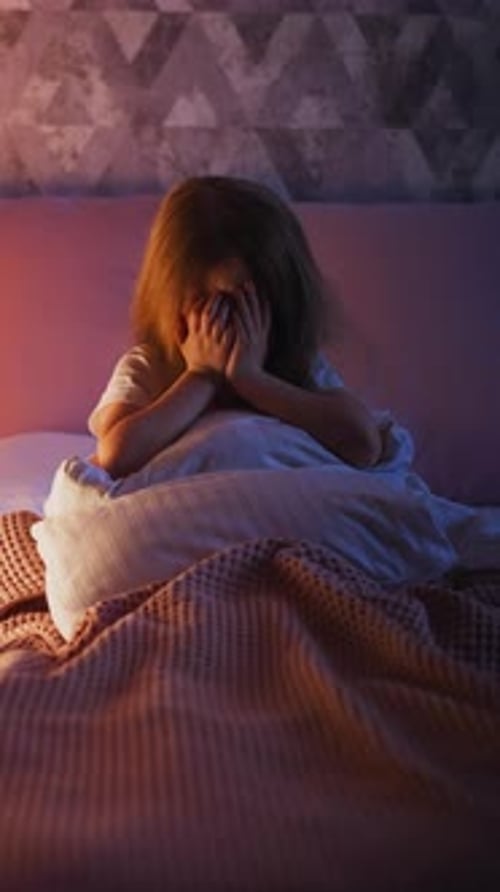 Scared Little Daughter Covers Face with Palms Crying on Bed