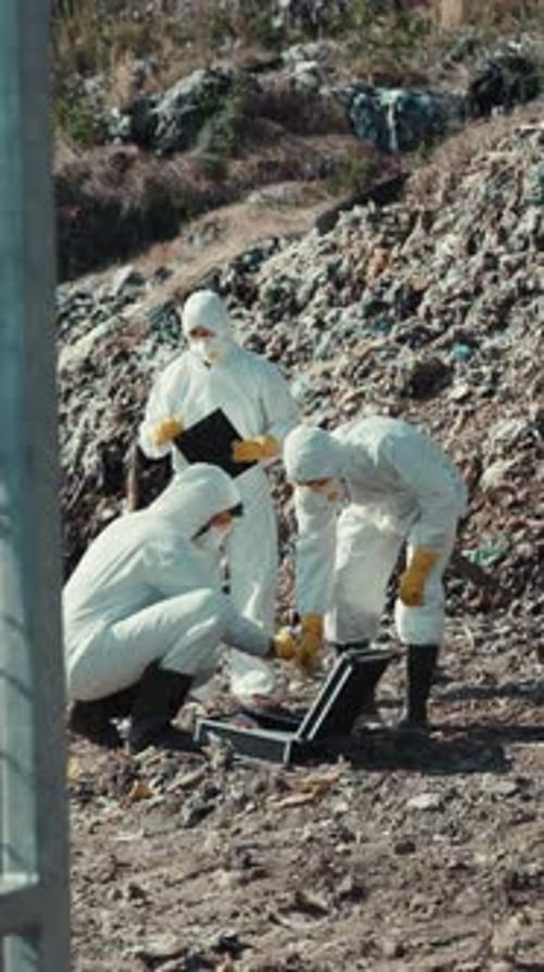 People in Hazmat Suits Inspecting Trash