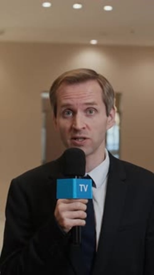 Man in Suit Speaking Into Microphone