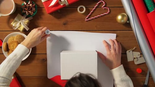 Gift Wrapping at Wooden Table with Christmas Decorations