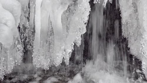 This is a close up of water flowing under a cover of ice into a stream in winter.