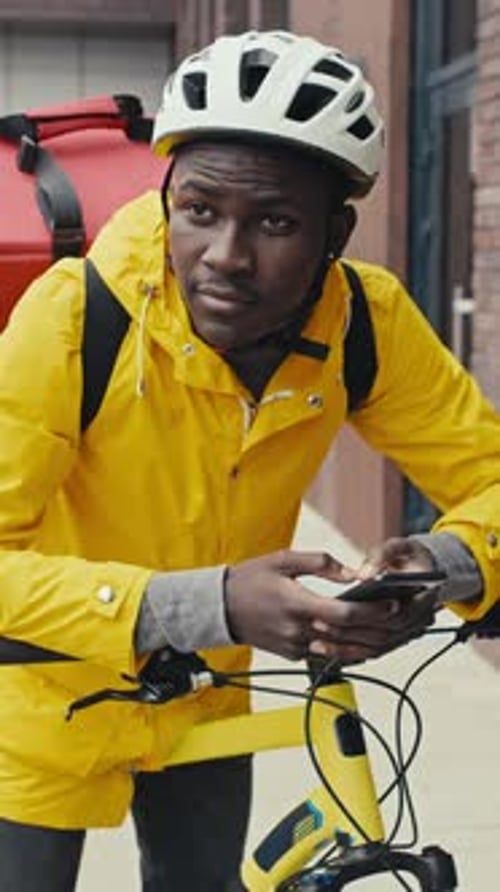 Delivery Worker Using Phone on City Street