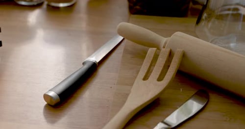 Die Nahaufnahme in Zeitlupe bewegt sich über Holznudelholz, Spatel, Buttermesser, Löffel, Küche