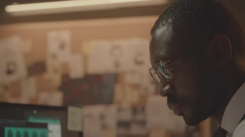 Tired African American FBI Agent Overworking in Office at Night