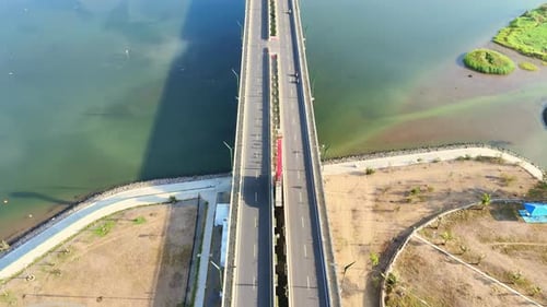 Reveal drone shot of Kretek II bridge over Opak River with green plantation and blue sky horizon on