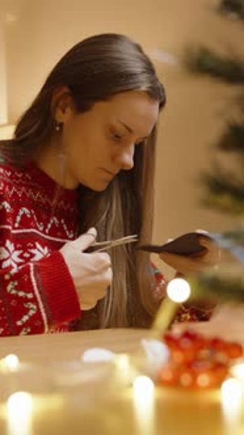 Woman Cutting Paper with Scissors for Christmas Crafts