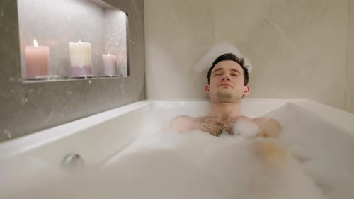 Man Relaxing in Bubble Bath with Candles