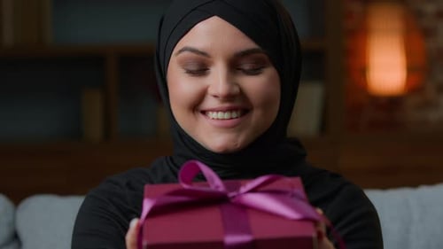 Smiling Woman in Hijab Hold Pink Gift Box with Ribbon Wishing Happy Birthday Christmas