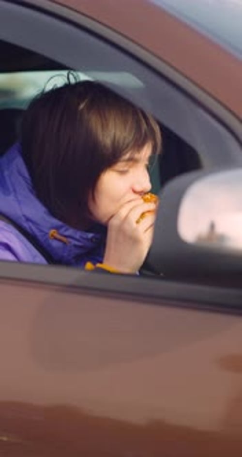 Young Adult Eating a Burger in a Car