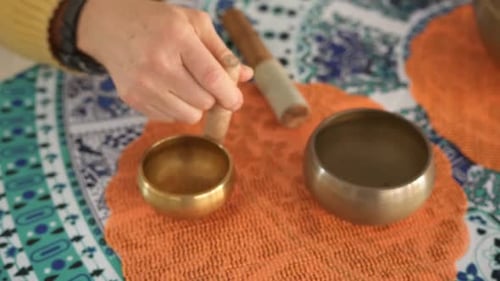 Close up of a hand playing a small bronze Tibetan singing bowl, colorful background