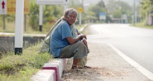 An Asian man who is a poor ragpicker or collects garbage and sells, sitting on the side of the road