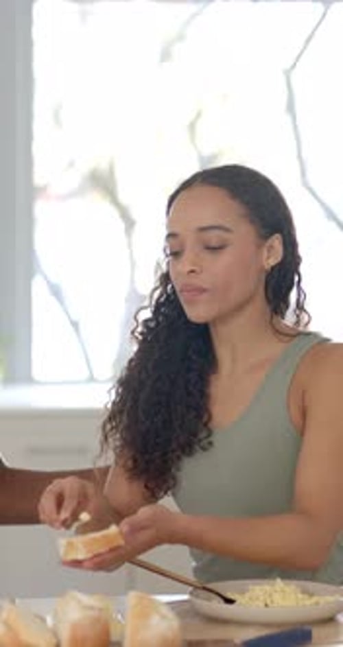 Vidéo verticale : une femme afro-américaine étalant sur du pain dans la cuisine, remettant une tranche à un homme partageant