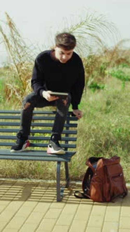 Man Picking Up Notes From The Backpack And Starting To Study On The Park Bench