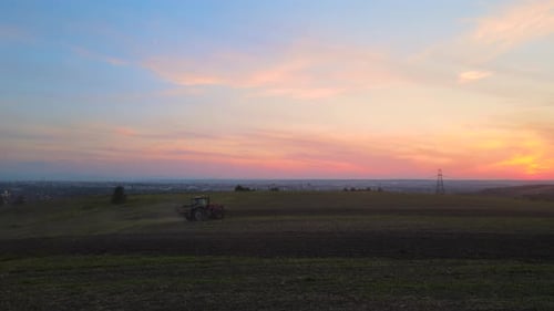 Tractor Spraying Fertilizers with Insecticide Herbicide Chemicals on Agricultural Field at Sunset