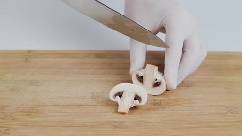 Hand Slices a Mushroom on Cutting Board
