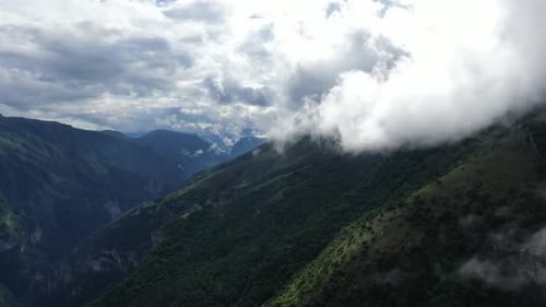 Landscape view of mountains and cloudy sky The scene is lush with trees Clouds cover the tops of