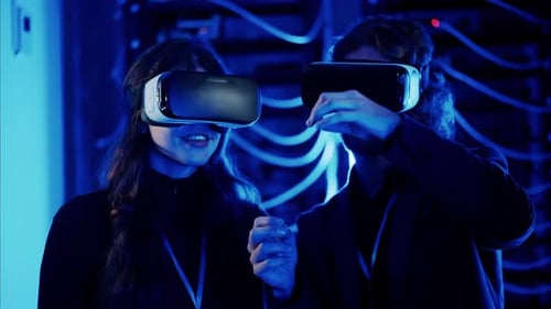 A man and a woman using Virtual Reality headsets in a server room