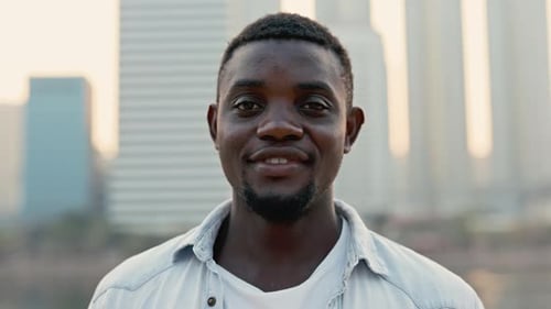 Portrait of African American Man Turning Head to Camera Standing Against Downtown District
