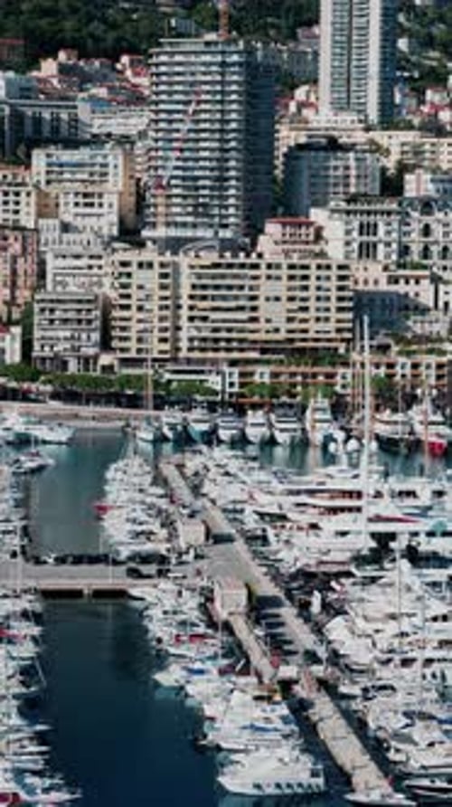 Aerial view of boats docked in the Monaco Marina with the skyline of the city on the background