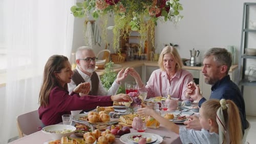 Family Holds Hands at Festive Easter Meal