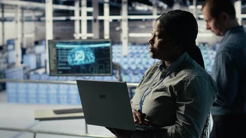 Data Center Admin Checks AI Dashboard Using Laptop During Rigs Systems Review