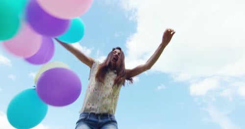 Happy Woman Jumps with Balloons on Sunny Day