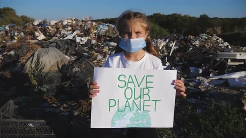 Child Holds Save Our Planet Sign at Landfill