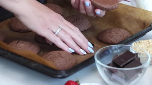 Hands Arranging Chocolate Cookies on Baking Sheet