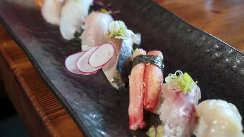 Chopsticks grab nigiri sushi from traditional japanese sushi assortment platter, close up slider 4K