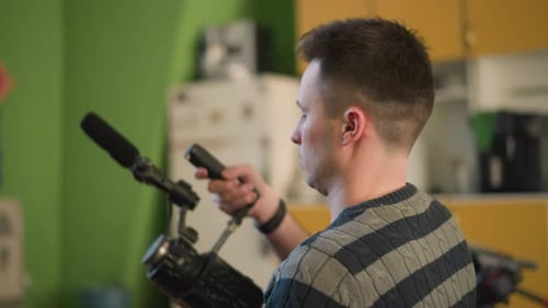 Young Man Holds Video Camera in Kitchen Setting