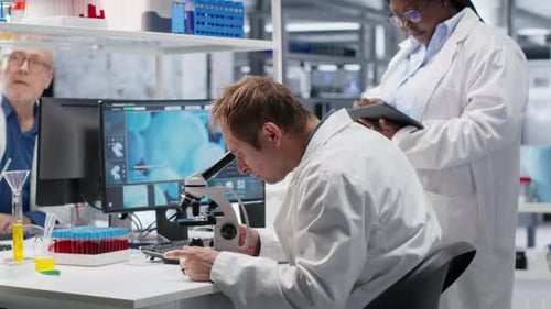 Equipe de funcionários estudando bandeja de amostra sob o microscópio para estudo de pesquisa