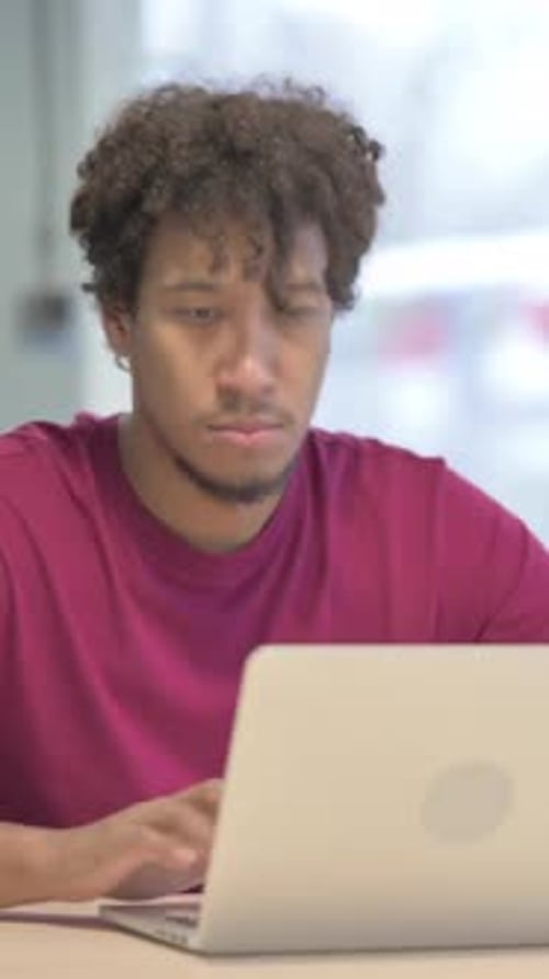 Young Man Uses Laptop and Smiles at Camera