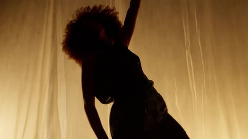 Elegant Woman Dancing in Studio with Curly Hair