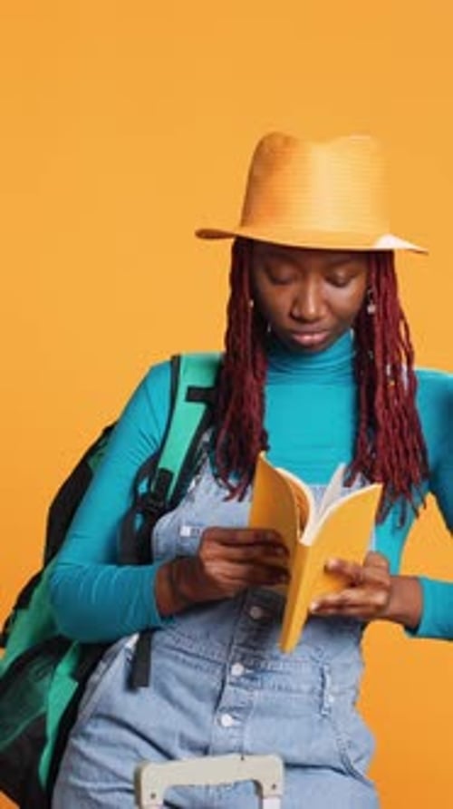 Young Woman Reads a Book on Luggage