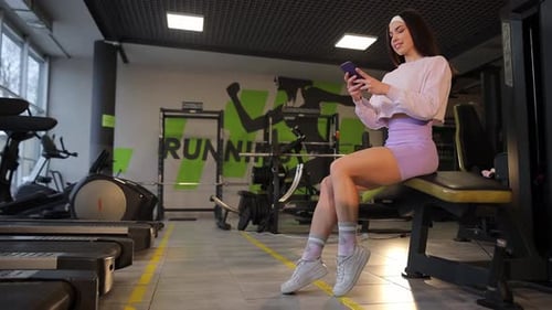 A Woman Uses Her Smartphone at the Gym Demonstrating Her Dedication to Fitness and Health