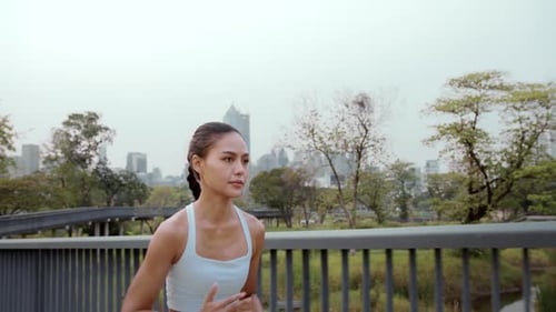 Young fitness woman in sportswear jogging in city park