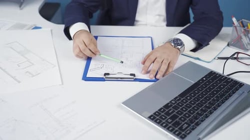 Architect male drawing on projects in office, working on laptop.