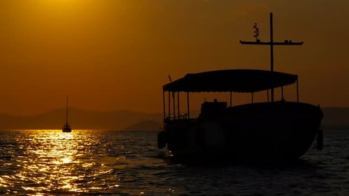 Boats Silhouetted Against Golden Sunset on Ocean