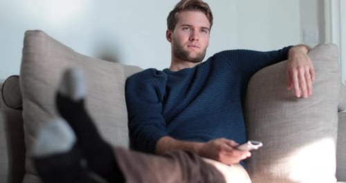 Relaxed Man Leans Back on Couch with Remote