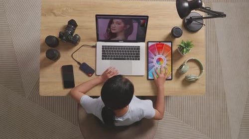 Top View Of A Woman Looking At The Color Schemes On A Tablet While Using A Laptop Editing Photo