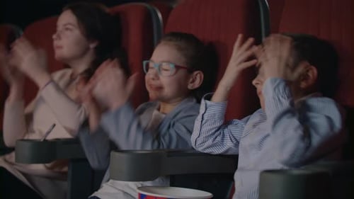 Children Got Scared In Cinema. Kids Are Frightened At Movie Theatre. Scared Children Cover Faces ...