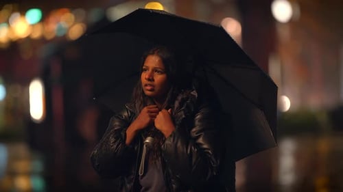 A Solitary Individual Holding an Umbrella in a Vivid Rainy Urban Night Scene Unfolds