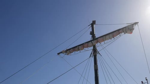 Der Mast des Piratenschiffs und die eingerollten Segel stehen vor einem klaren Himmel, Sonnenstrahlen werfen einen Schein, perfekt für