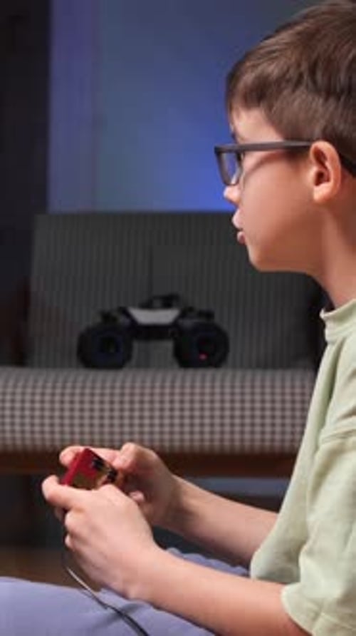 Boy Plays Video Game with a Red Controller