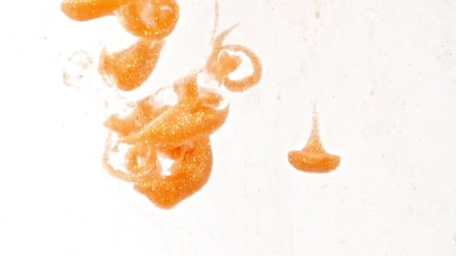 Flowing Orange Glitter Paint on White Background