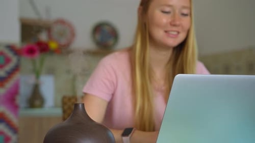 The Video Features a Young Woman Sitting at a Desk in Her Apartment Working on Her Laptop